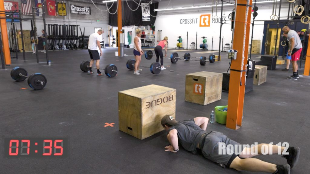 Athletes training in a CrossFit box with barbells and plyo boxes