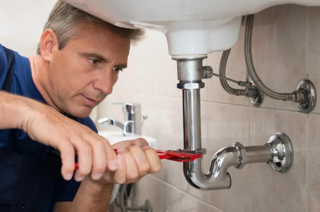 Professional plumber fixing sink pipe