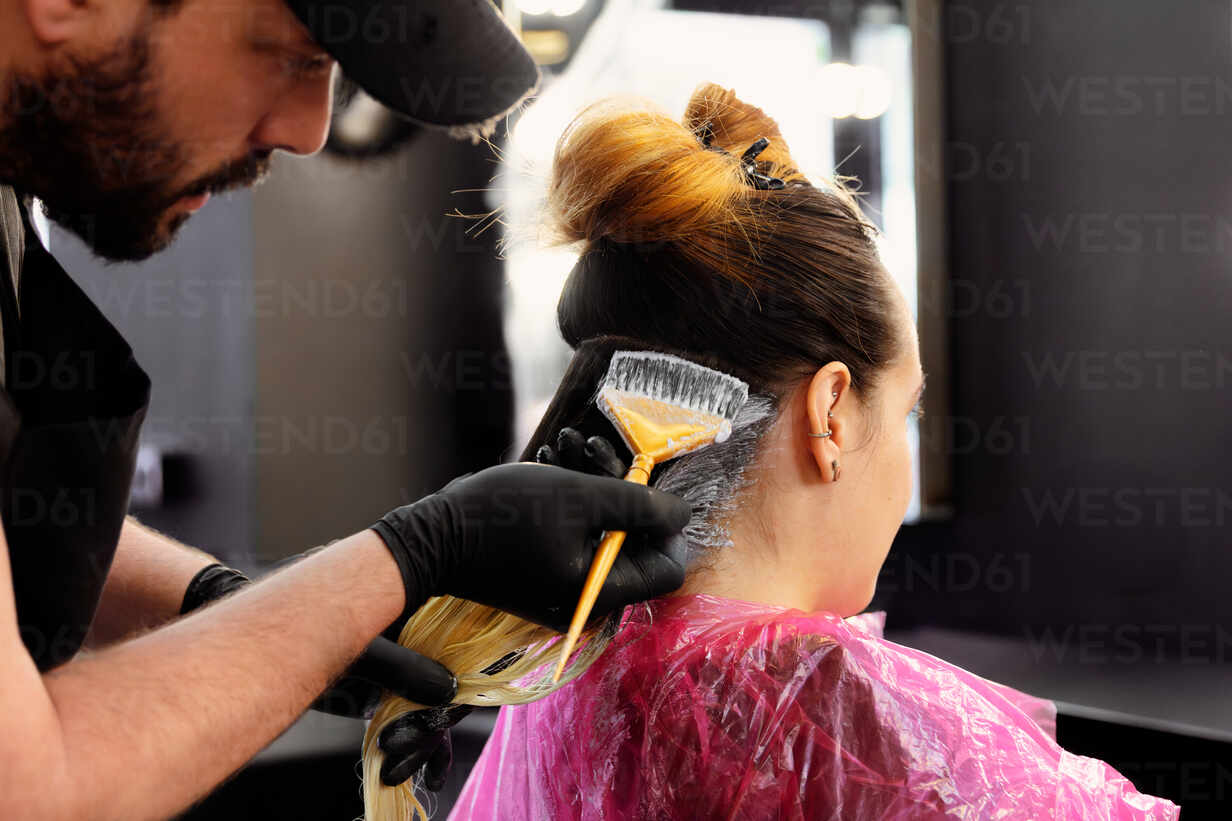 Professional stylist colouring client's hair