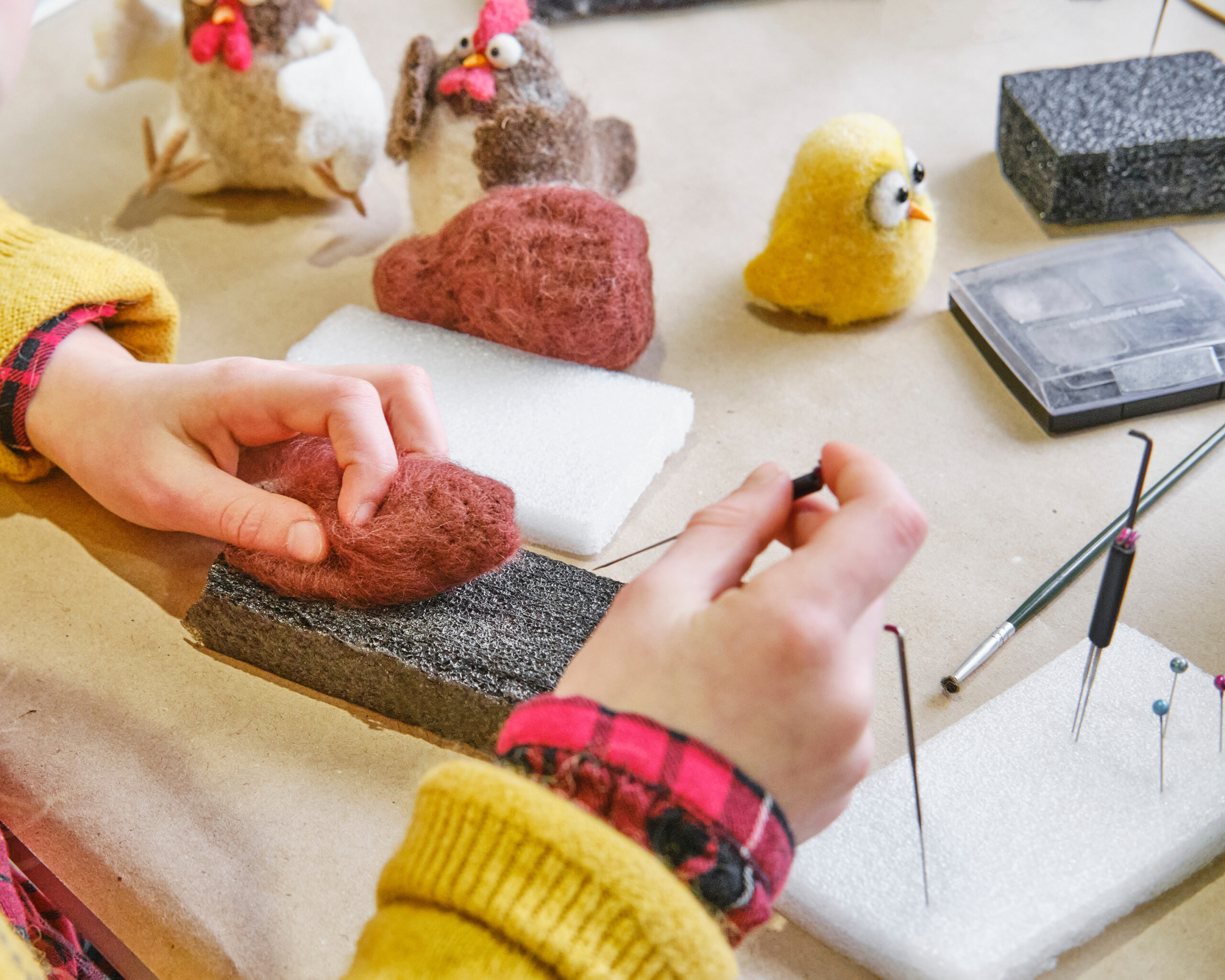 Hands needle felting wool in a cozy workshop