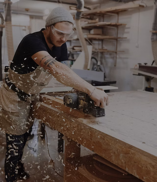 Skilled woodworker hand-planing a solid wood board in our Calgary workshop